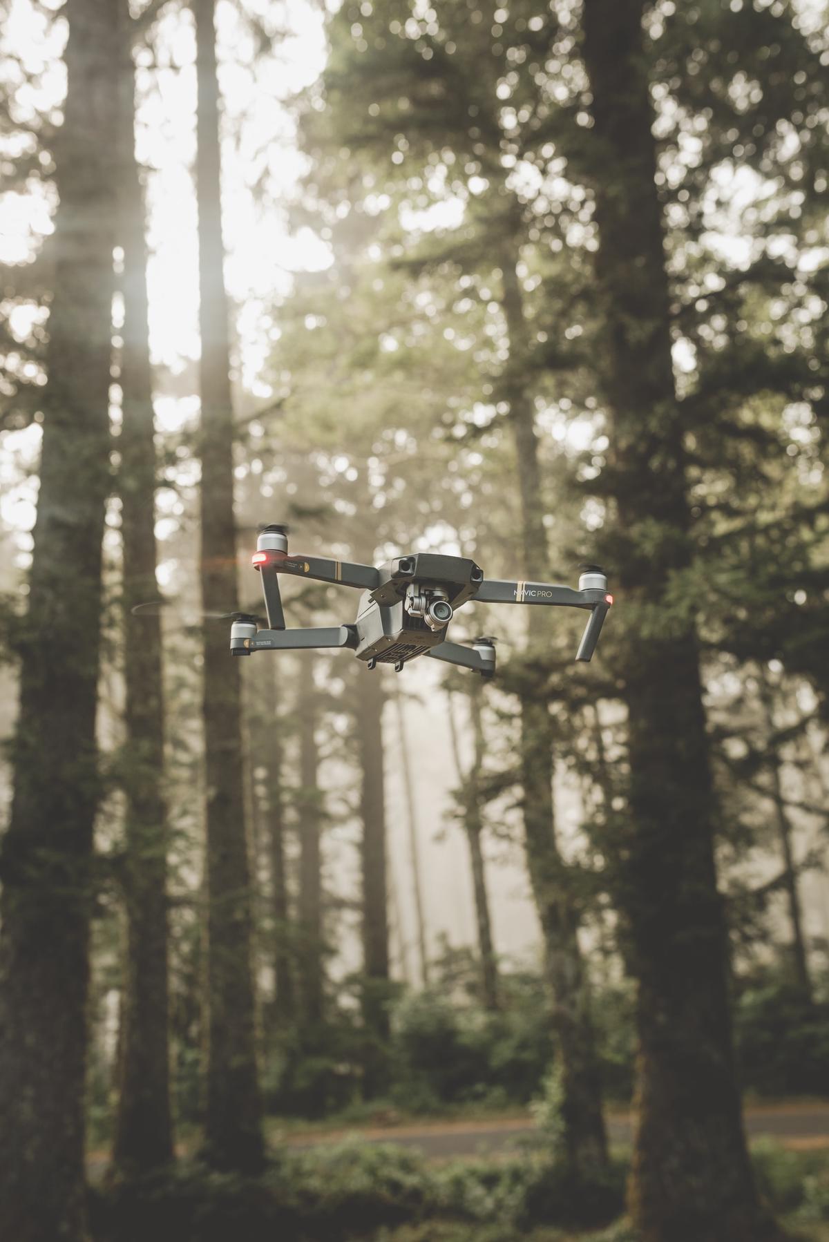 An image showing a DJI drone in flight over a scenic landscape, capturing stunning aerial footage