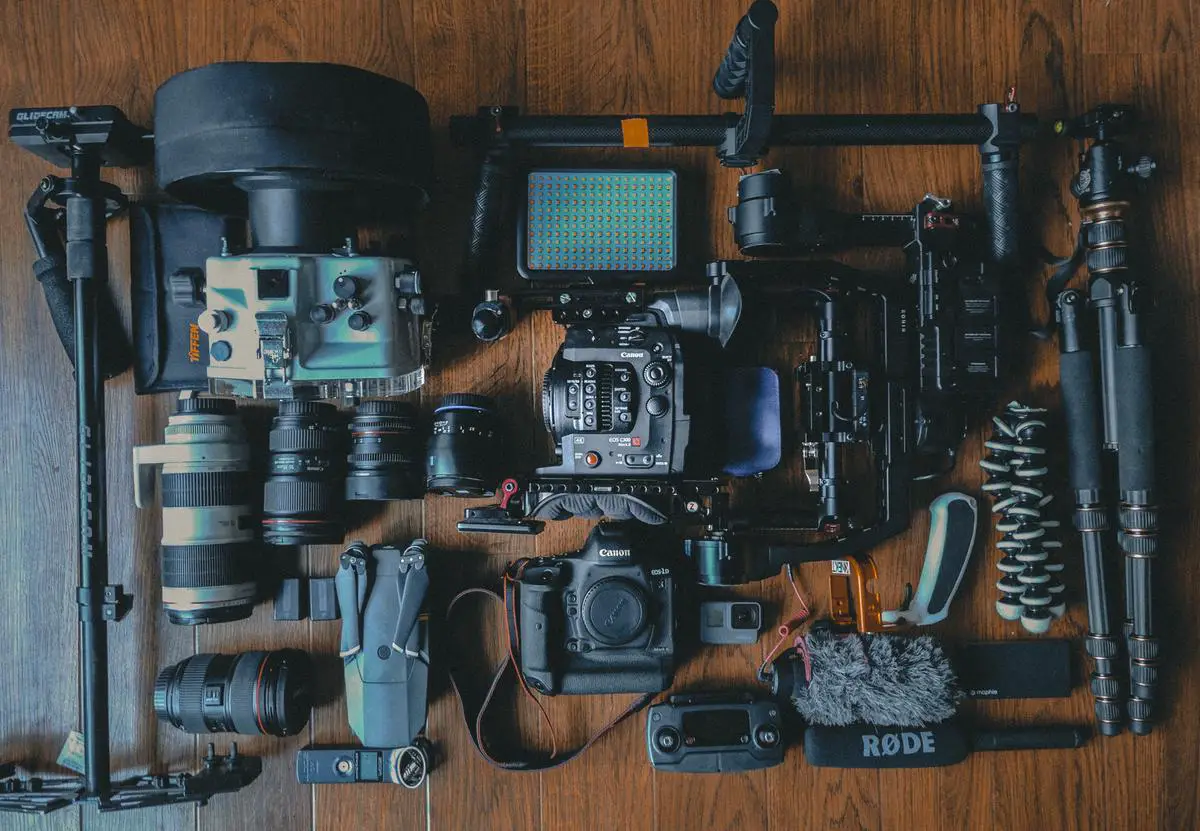 A camera, lens filters, lens hoods, and cleaning tools arranged on a wooden table, ready for travel photography.