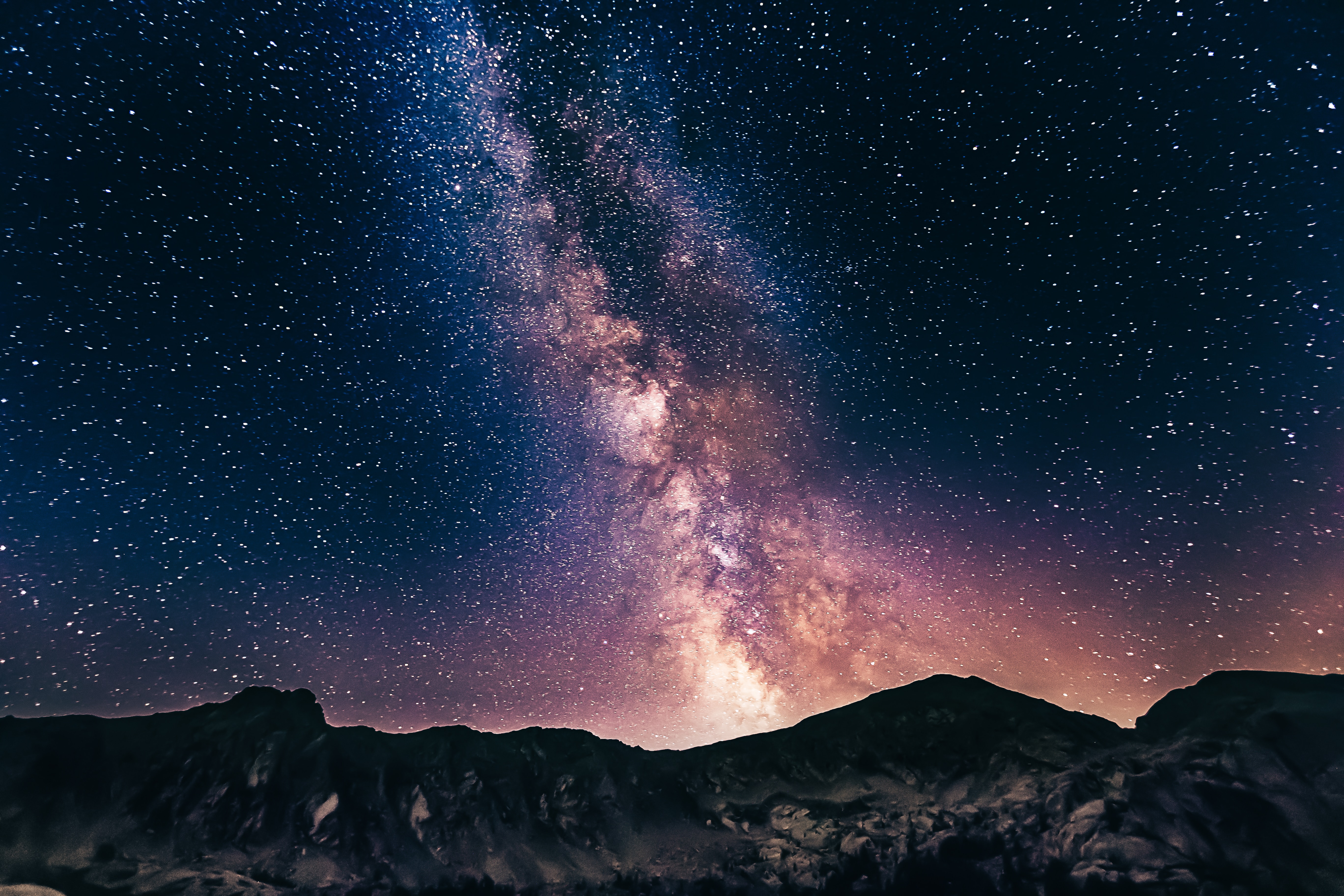 A stunning image of the Milky Way galaxy with stars and dust visible in the background, shot using long exposure photography techniques. The image has been processed to reduce noise and enhance color and contrast.