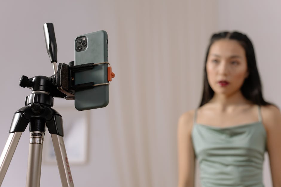 A person vlogging with a smartphone, tripod, and LED lights, with a sunlit room in the background