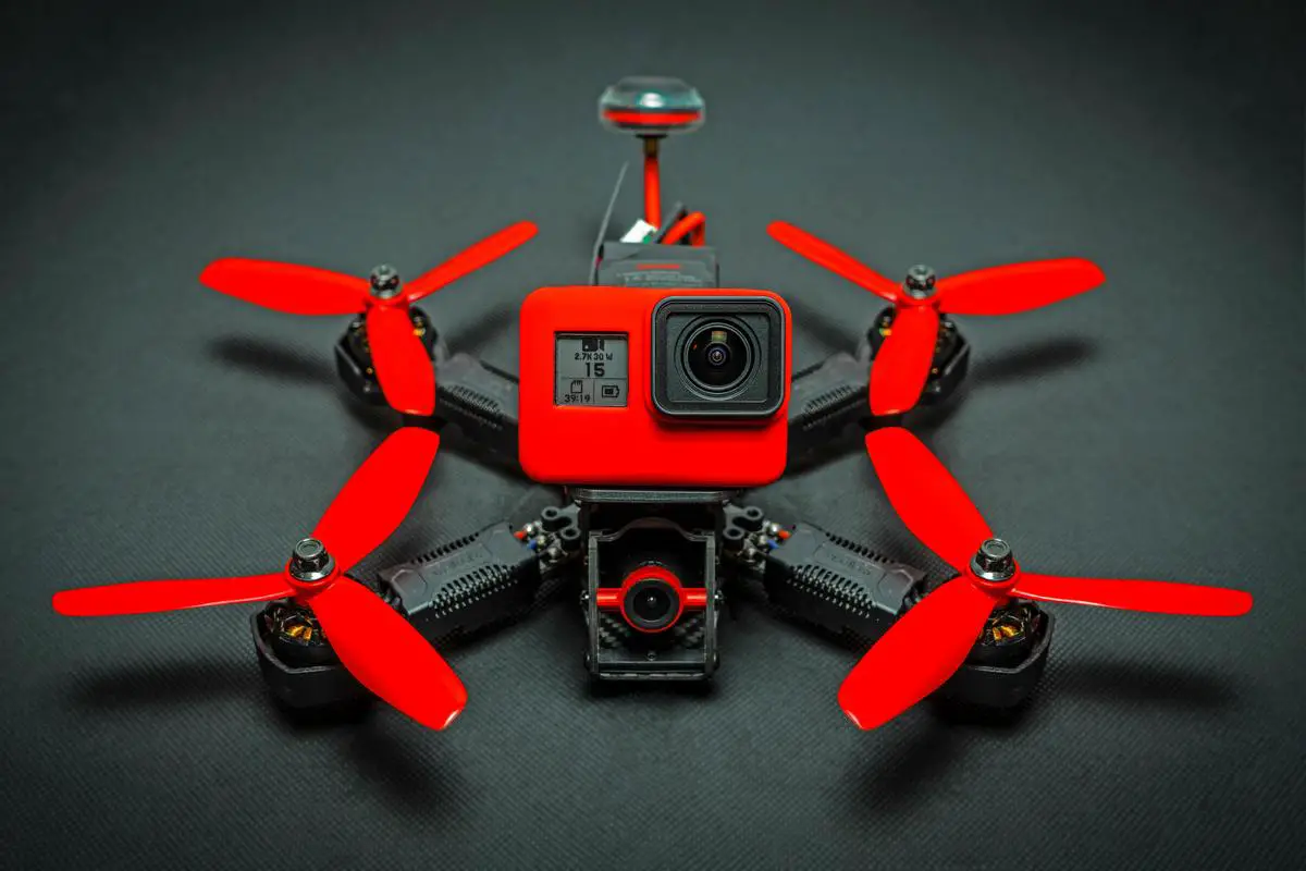 A racing drone with a carbon fiber frame, powerful motors, and lithium polymer batteries. The pilot is holding the controller, with the drone ready for takeoff.