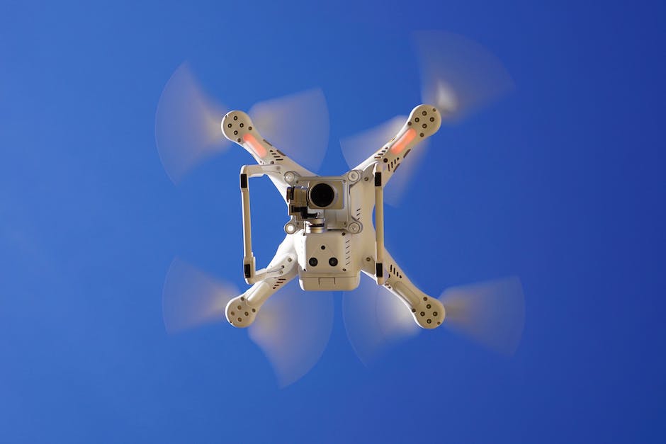 A person operating a drone and looking up at a clear blue sky.