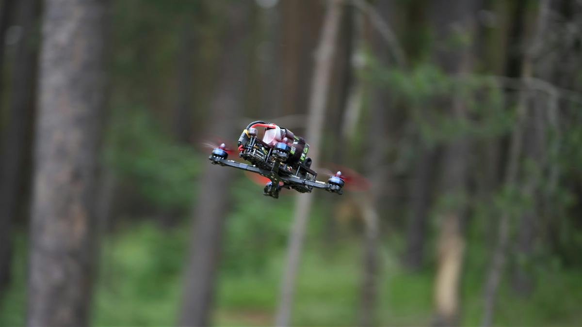 An image depicting a person controlling an FPV drone and gazing at it in awe