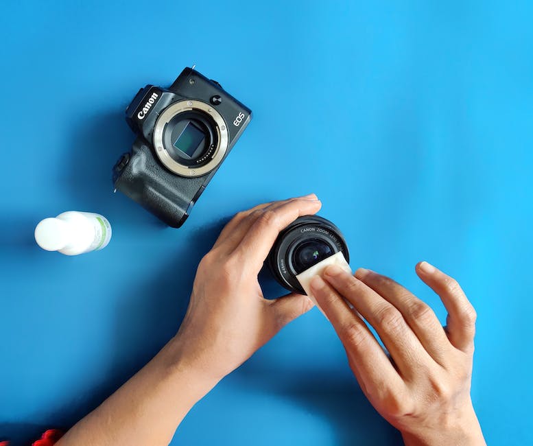 A camera lens being cleaned with a brush and microfiber cloth