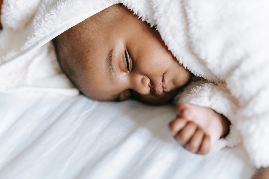 A photograph of a newborn baby wrapped in a soft blanket, peacefully sleeping on a bed.