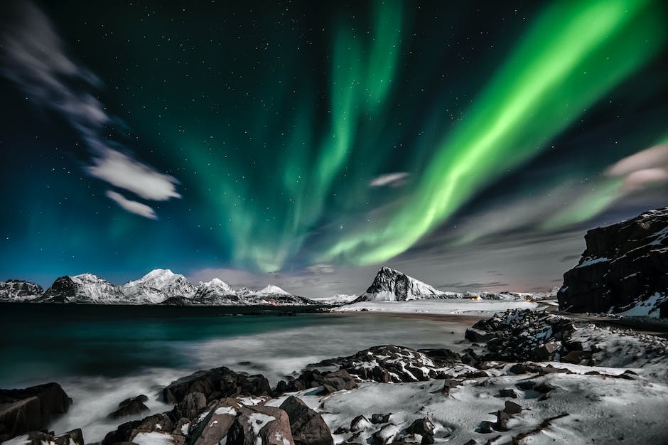 A stunning photo of the northern lights lighting up the sky with multiple colors in a long exposure shot.