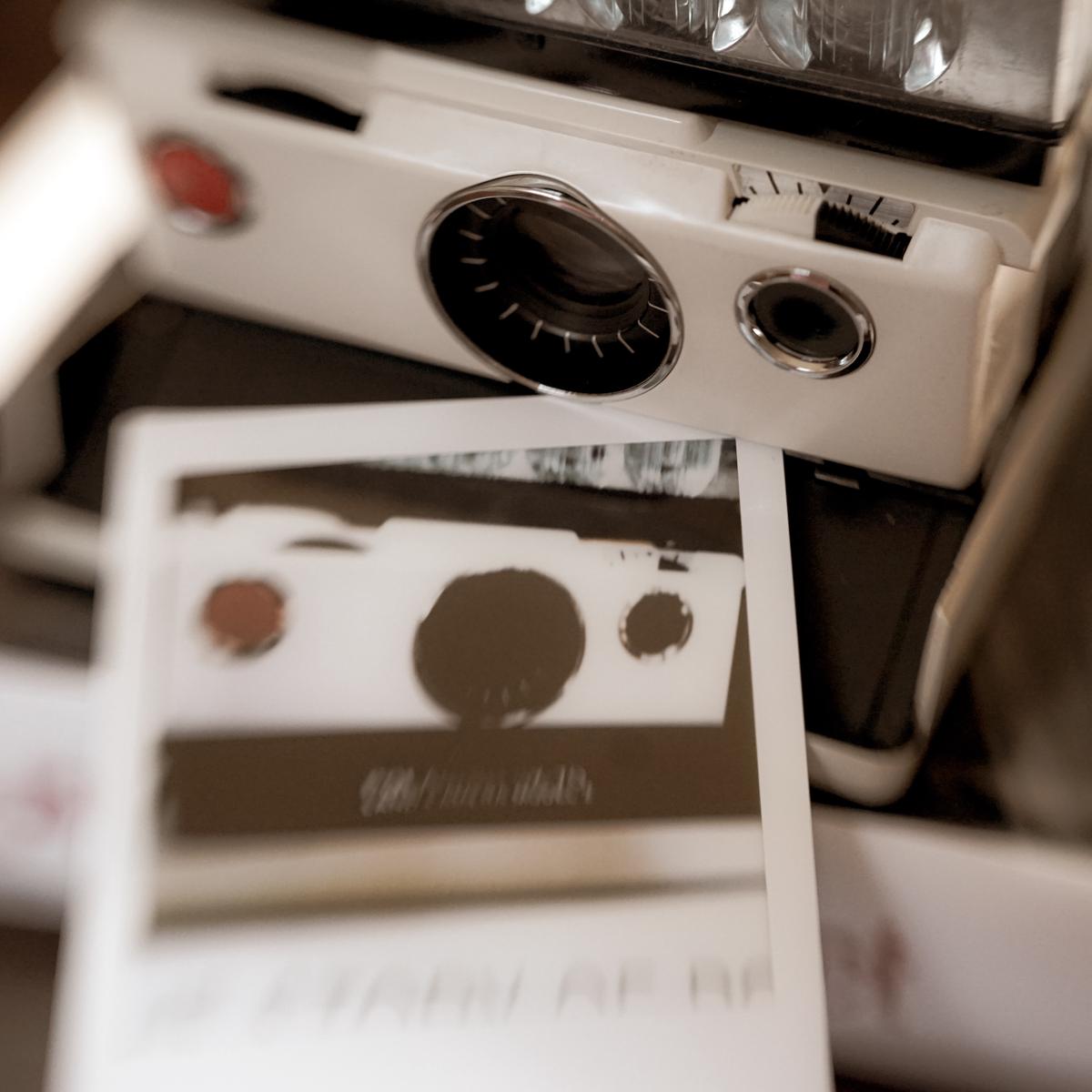 Image of a Polaroid SX 70 camera from the 1970s showcasing its iconic chrome and leather design, collapsible SLR viewfinder, and unique instant film format.