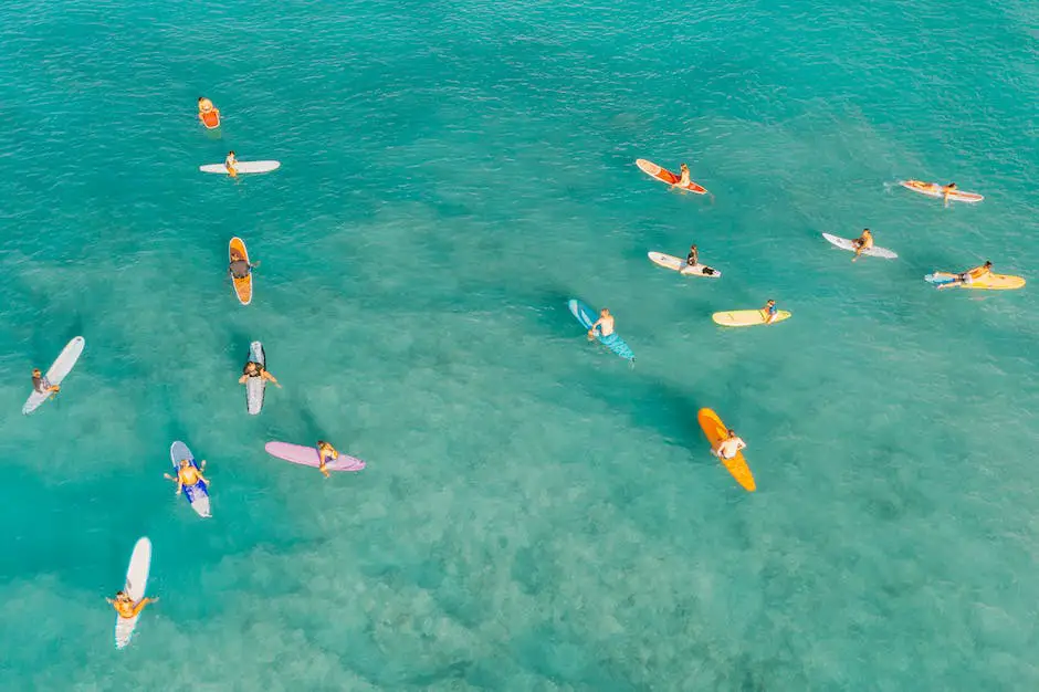 A stunning aerial view of several surfers catching waves on a beach with bright blue water and a clear sky above.